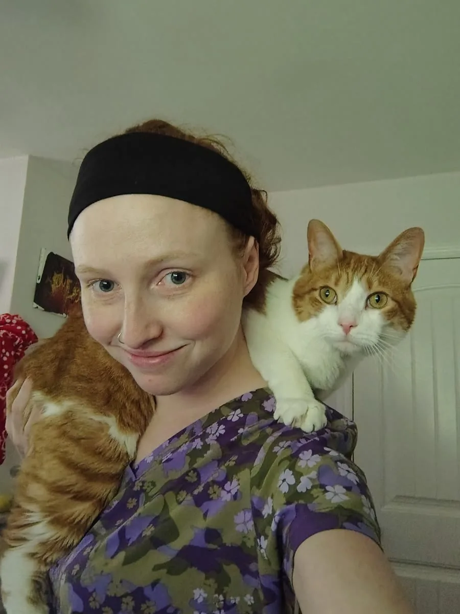 Hannah Comer, Certified Veterinary Technician, with an orange-and-white cat resting on her shoulder