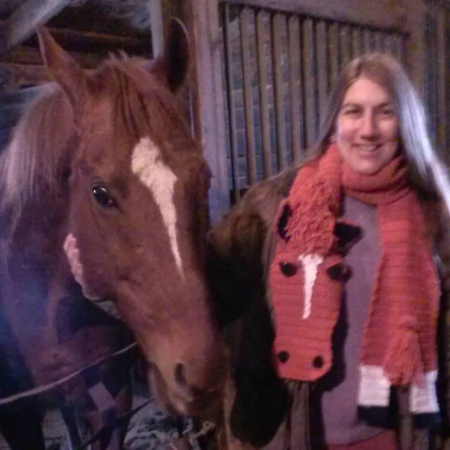 Dr. Lyn Shelton, Veterinarian, smiling next to one of her horses